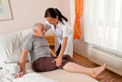 nurse assisting patient in getting up in bed